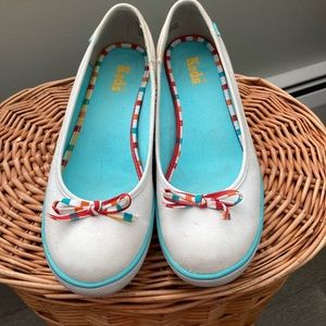 Women’s white slip on Keds with wedge heel and colorful trim.